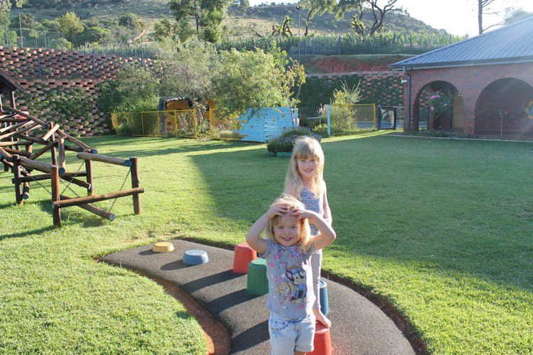Two little girls are standing on a path in a park