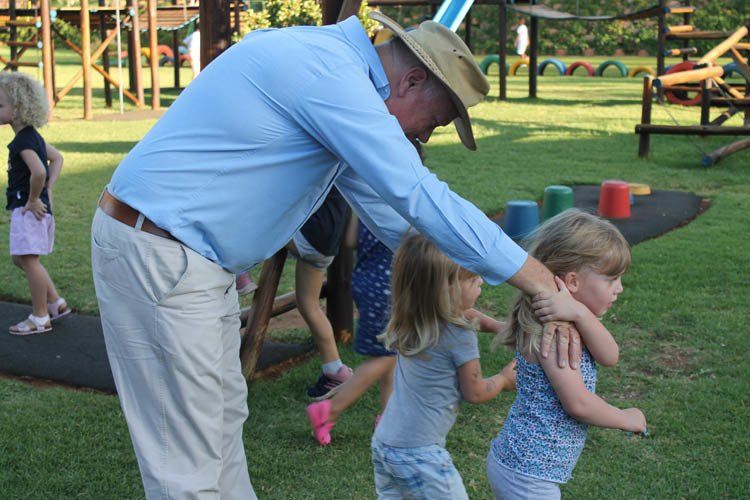 A man in a hat is standing next to two little girls
