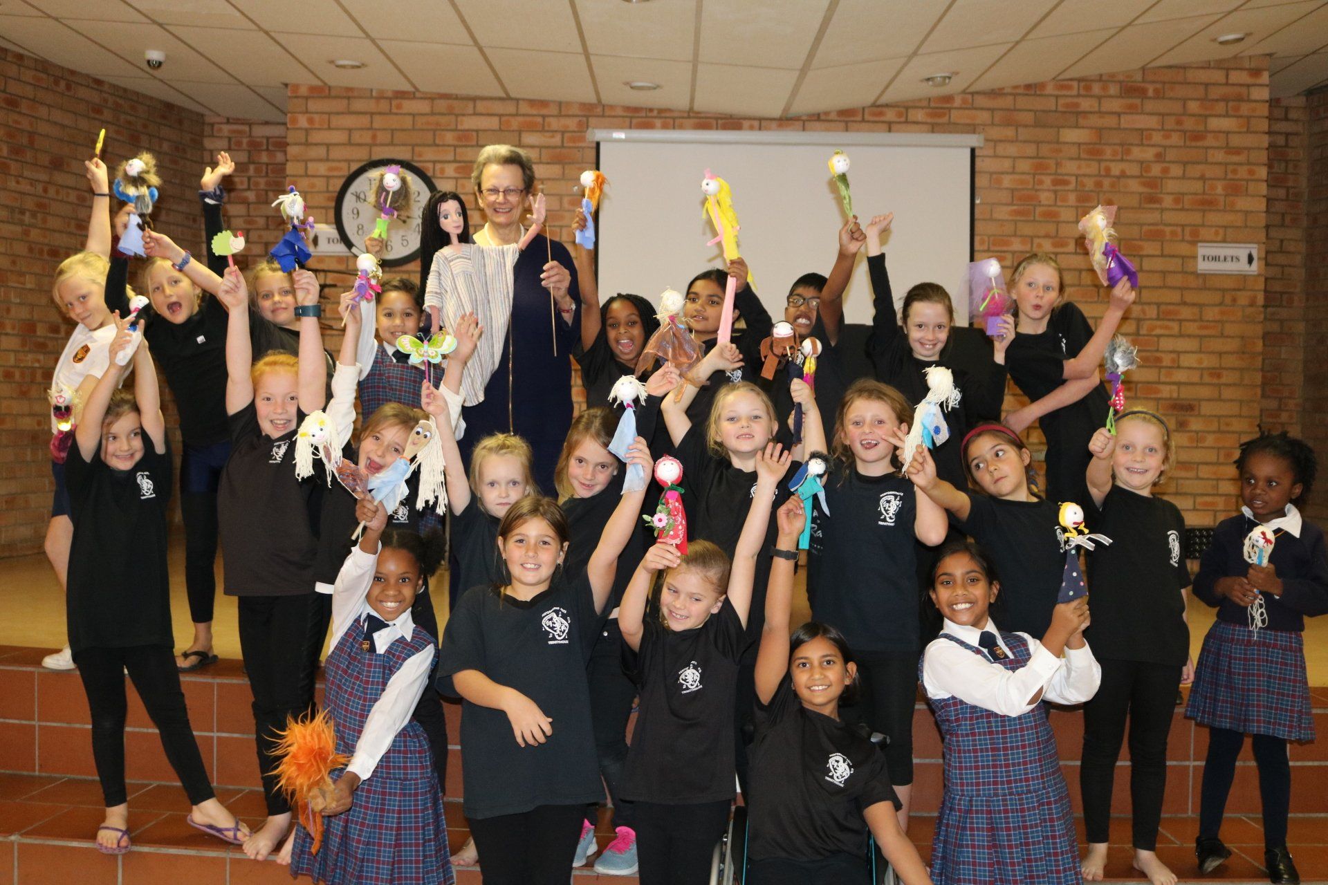a group of children are posing for a picture with their hands in the air