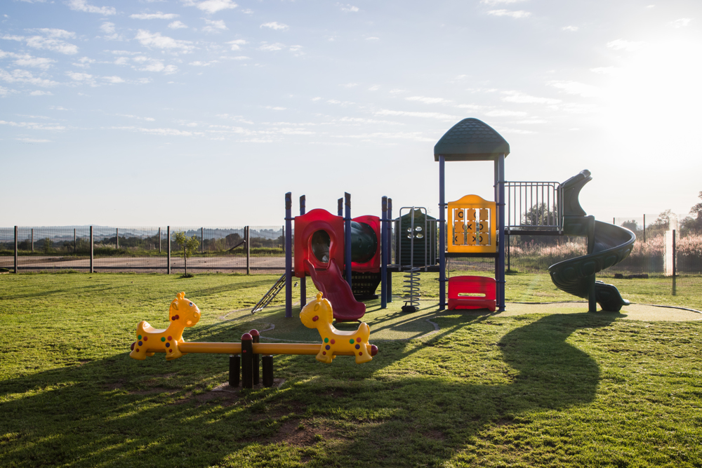 there is a playground in the middle of a grassy field .