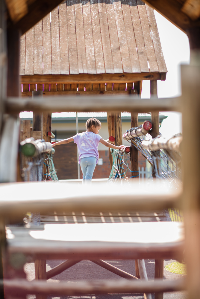 a little girl is playing in a wooden playground .