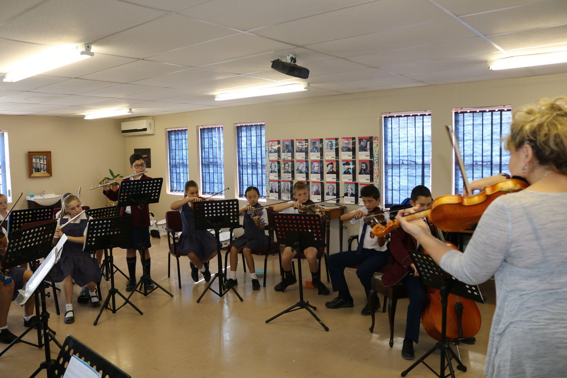 a woman is playing a violin with a class of music students .