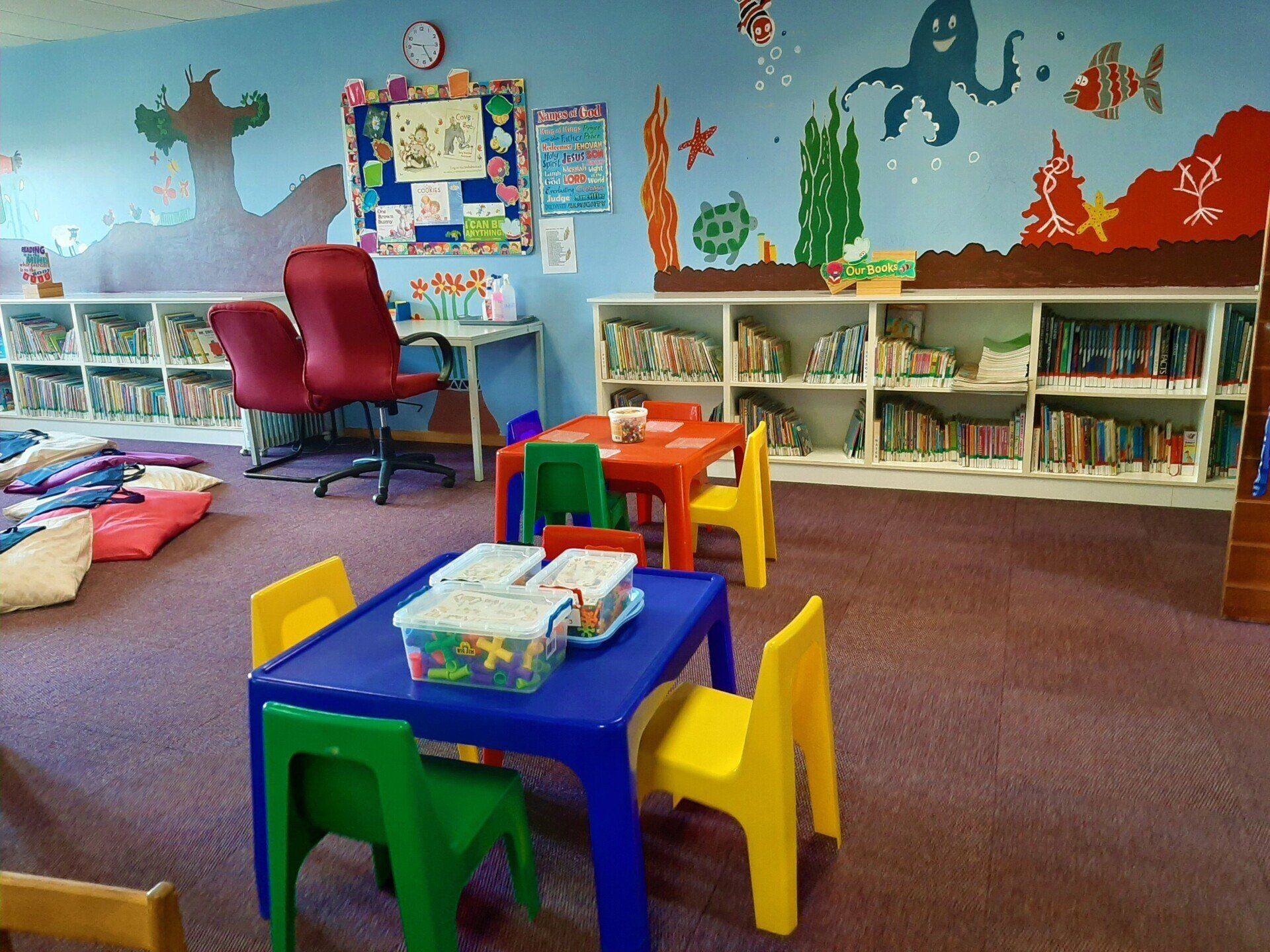 Classroom with tables and chairs and a mural on the wall