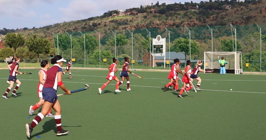 a group of girls are playing a game of field hockey on a field .