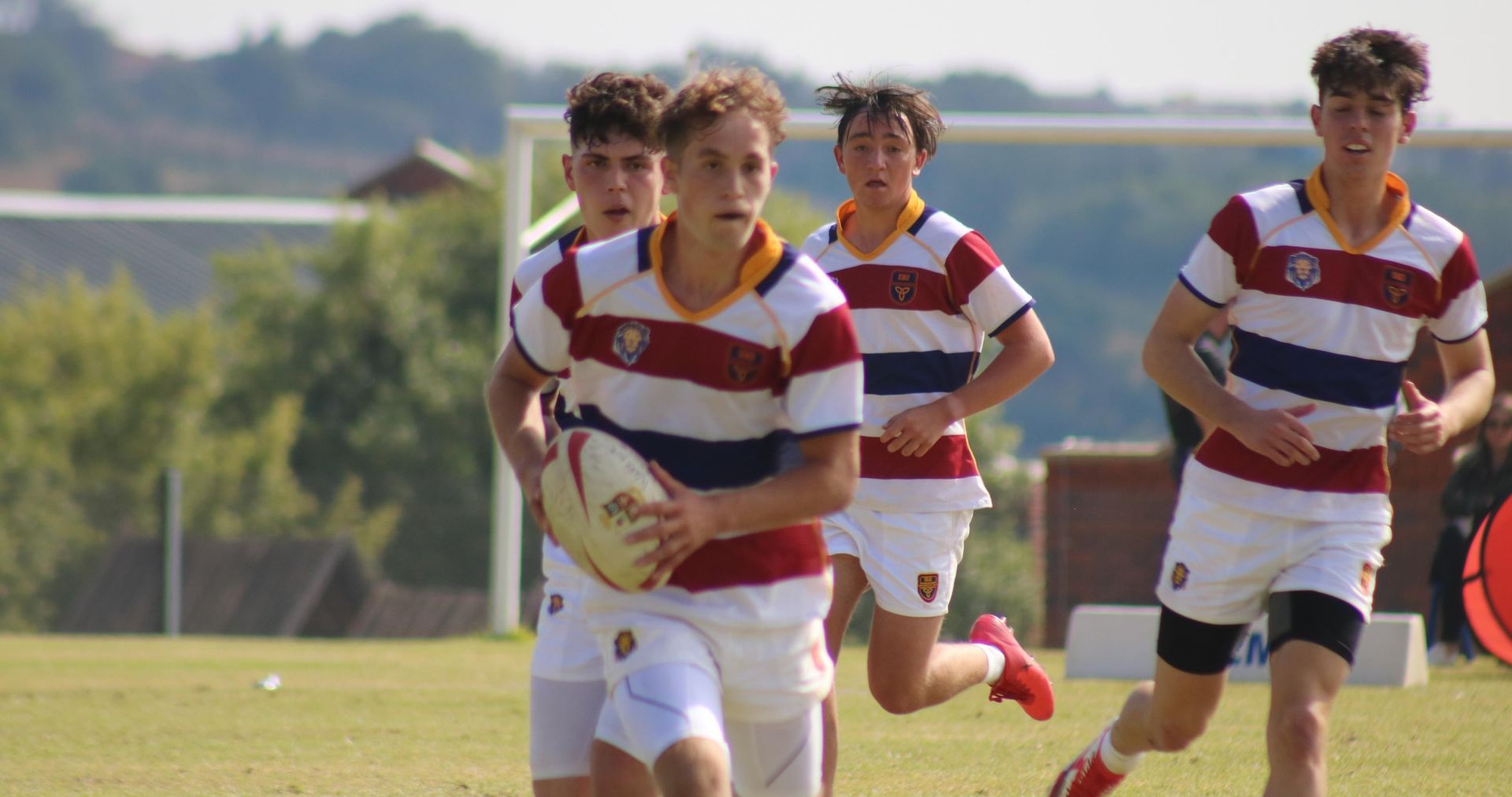 a group of young men are running with a rugby ball on a field .