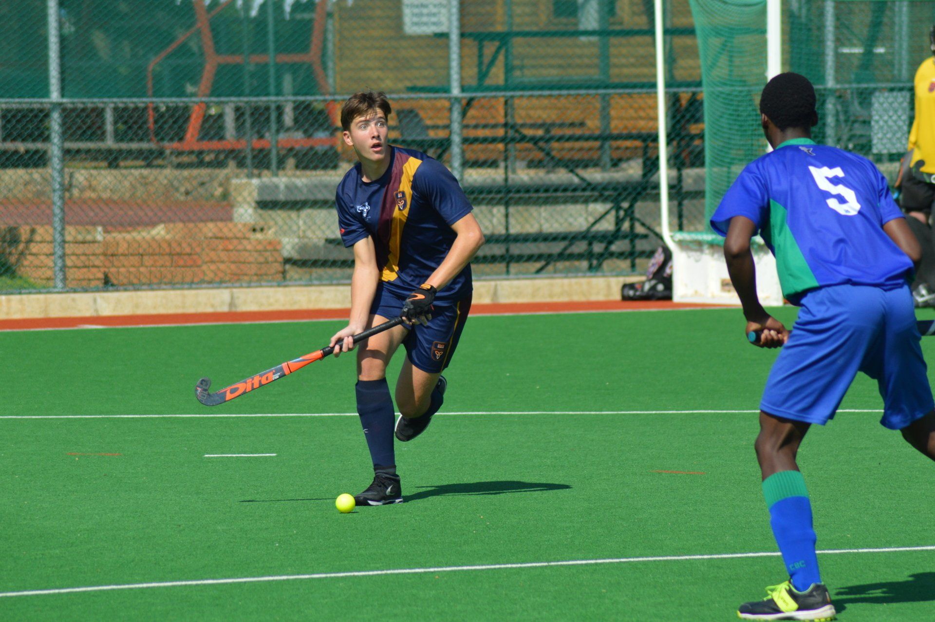 A man with the number 5 on his jersey is playing field hockey