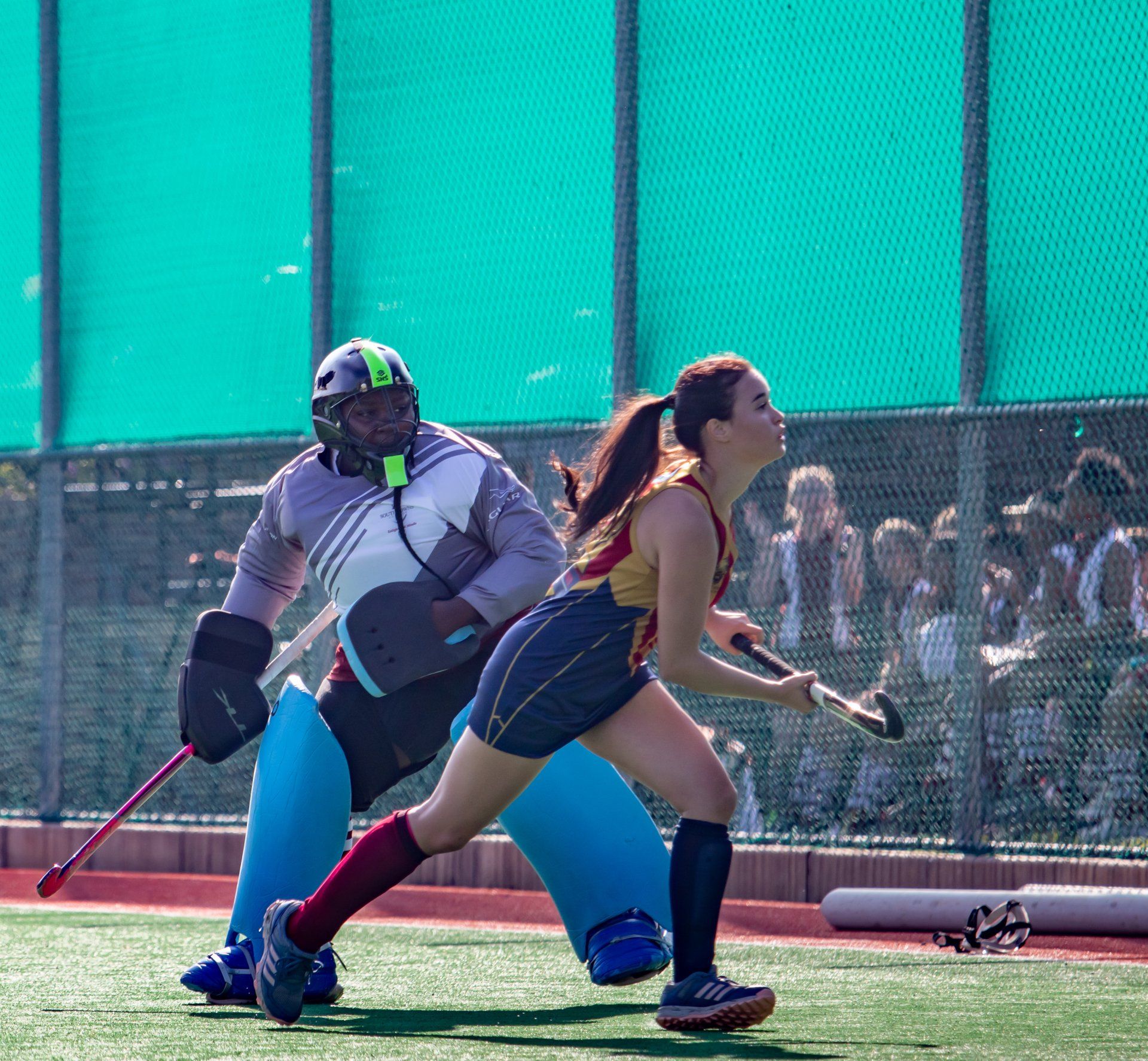 A man and a woman are playing field hockey on a field