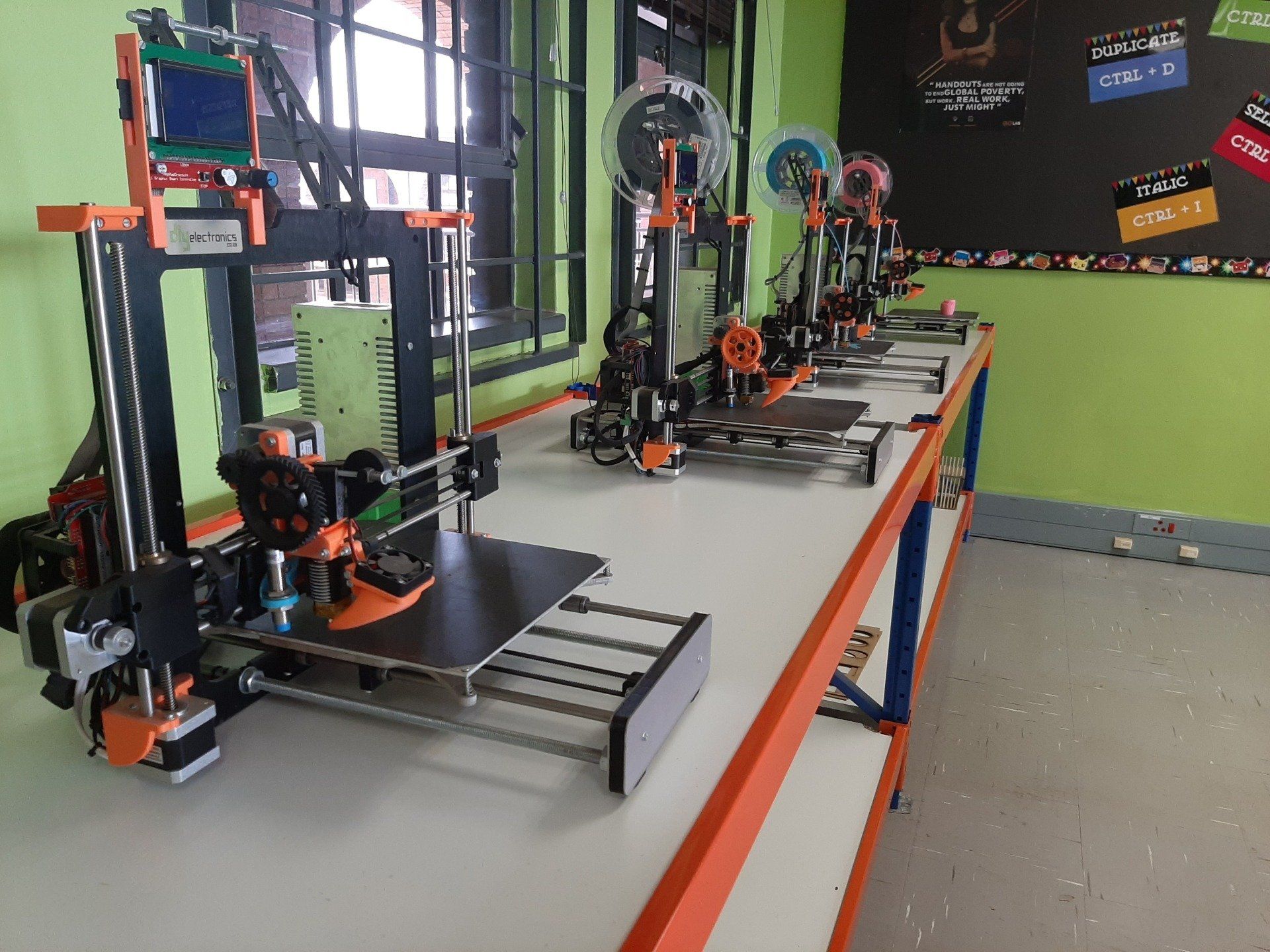 a row of 3d printers are sitting on a table in a room .
