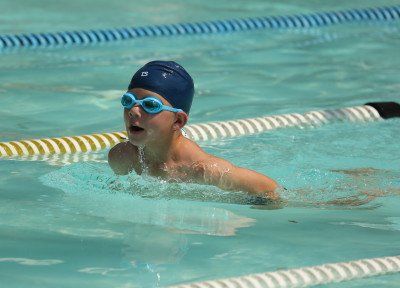 a young boy is swimming in a swimming pool .