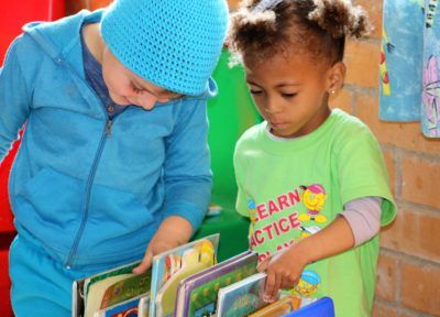 a boy and a girl are looking at books together .