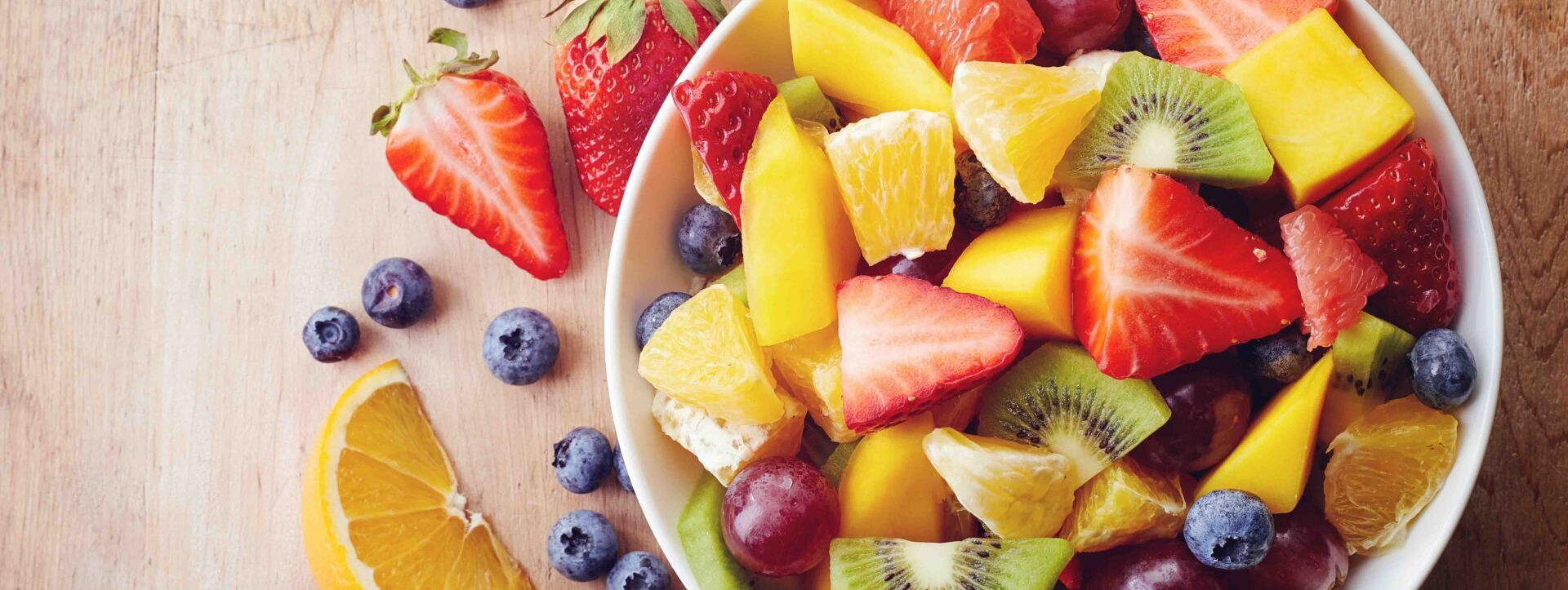 A bowl of fruit salad on a wooden table.