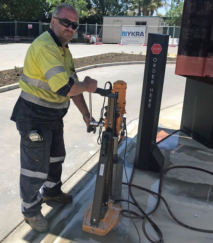 A man standing next to a machine that says mykra on it