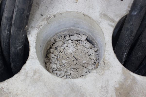 A close up of a hole in a concrete wall with rocks in it.