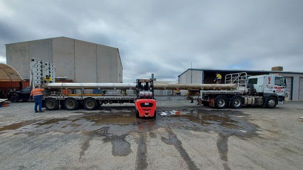 Houseboat pontoons being loaded onto a truck