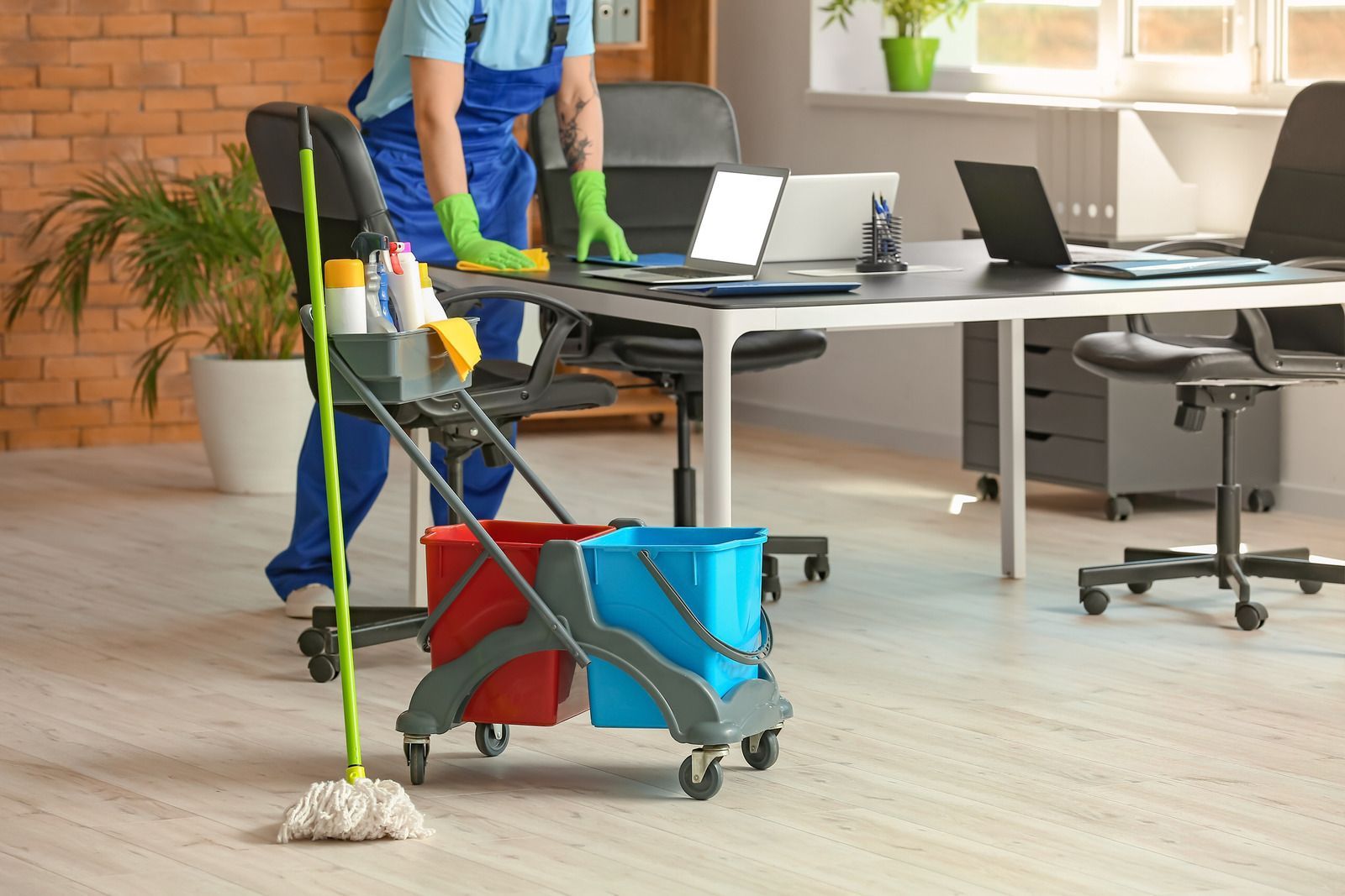 A man is cleaning an office with a mop and bucket.