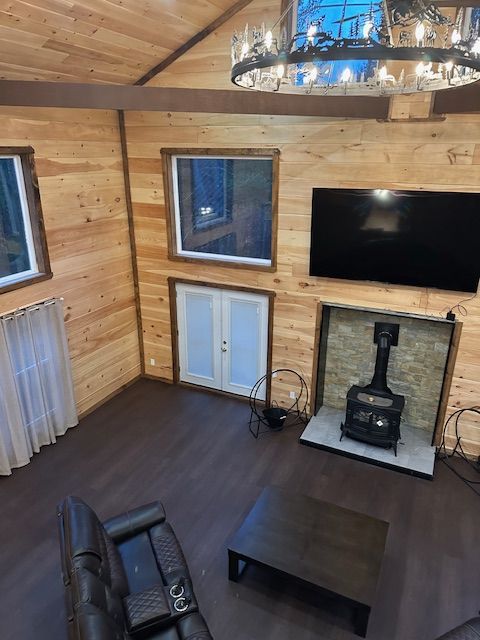High-angle view of a wood-paneled living room with a fireplace, TV, and dark wood floors.