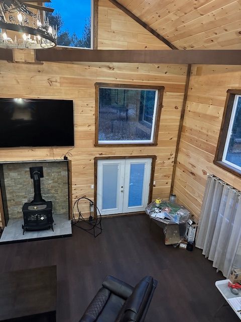 Interior of a cabin with wooden walls, a fireplace, and glass doors to outside.