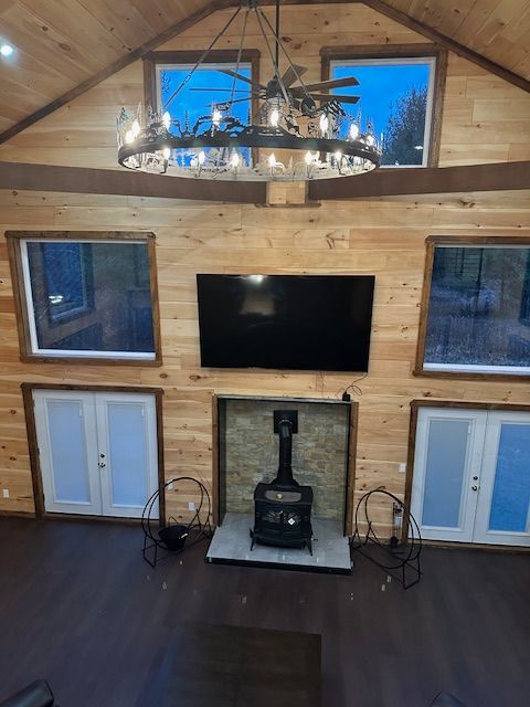 Living room with wood paneling, TV above fireplace, windows, and chandelier.