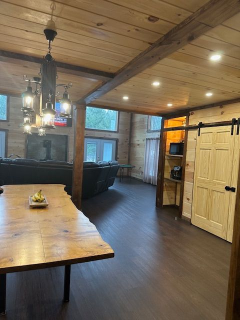 Wooden-paneled interior with wood beam ceiling, dark floors, and a dining table.