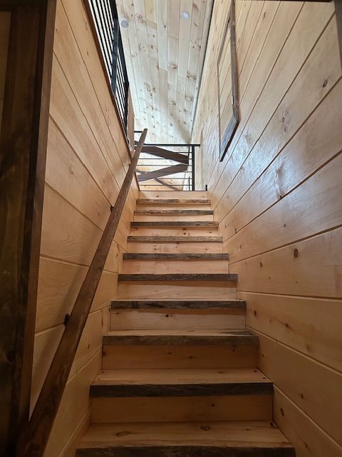 Wooden stairs leading up to an upper level with matching wood walls and ceiling, interior.