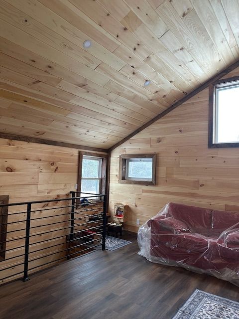 Interior with wood walls and ceiling. Sofa covered in plastic. Metal railing. Windows.