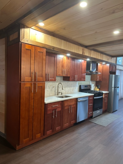 Kitchen with wooden cabinets, stainless steel appliances, and wood paneling on the walls and ceiling.