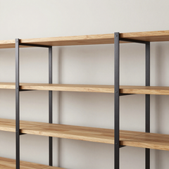 Estantería minimalista de madera y metal negro sobre una pared blanca lisa.