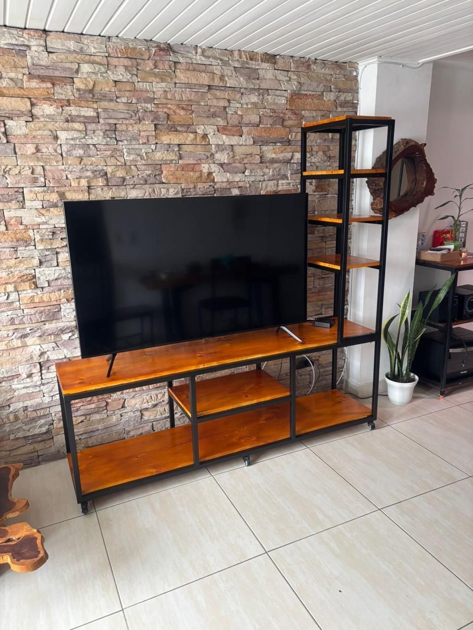 Mesa rústica de madera en una habitación minimalista con patas de metal negro y estantes de pared.