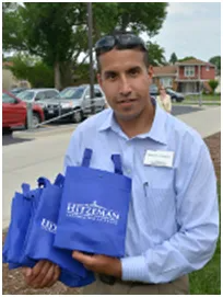 Man holding blue bags outdoors, likely promoting a business.