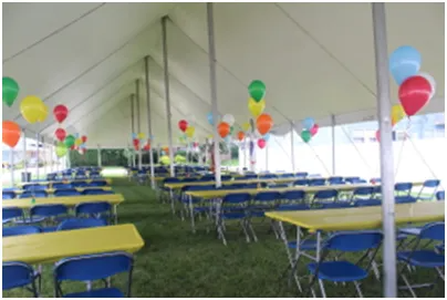 Inside a tent: Tables, chairs, and colorful balloons for an event.