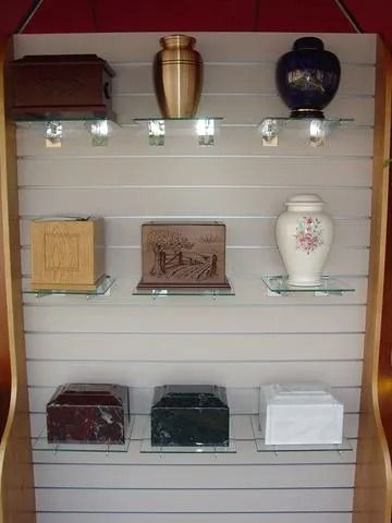 Display shelf with nine cremation urns of various shapes, colors, and materials.