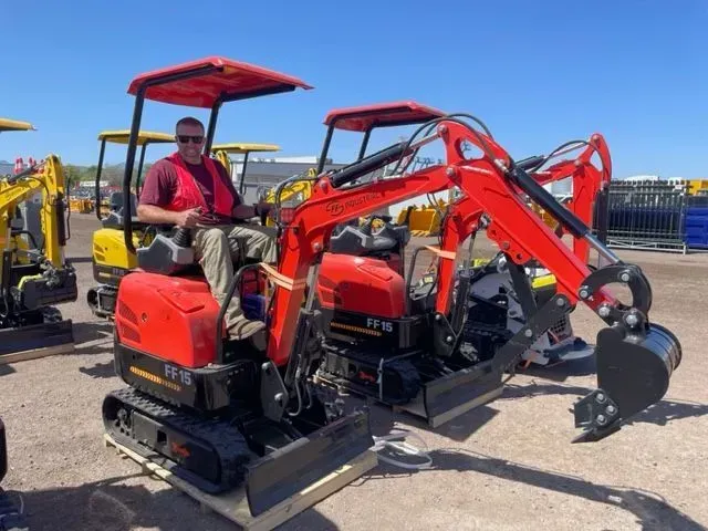 A man is sitting on a small red excavator