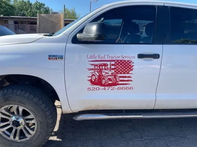 A white truck with little red tractor services written on the side