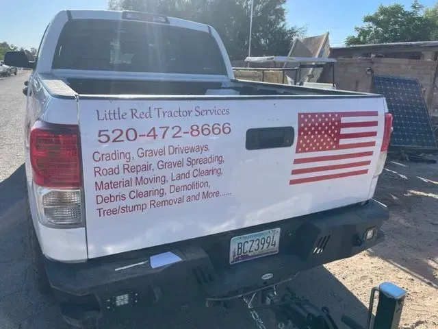A white truck with an american flag on the back is parked on the side of the road.