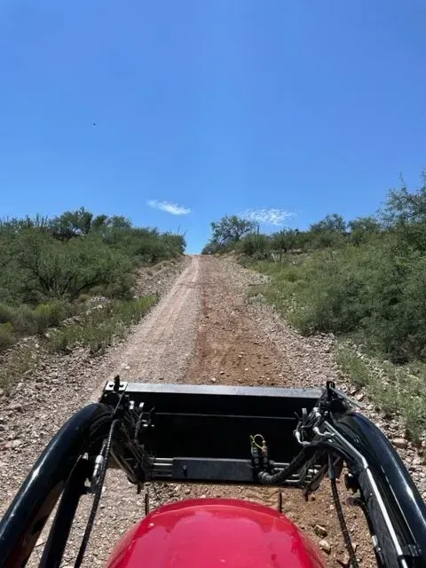 A red vehicle is driving down a dirt road.