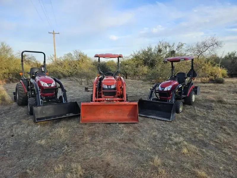 Three tractors are parked next to each other in a field.