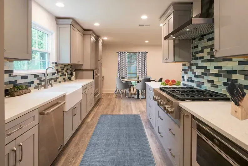 Gray kitchen with light countertops, blue backsplash, and a blue runner rug.