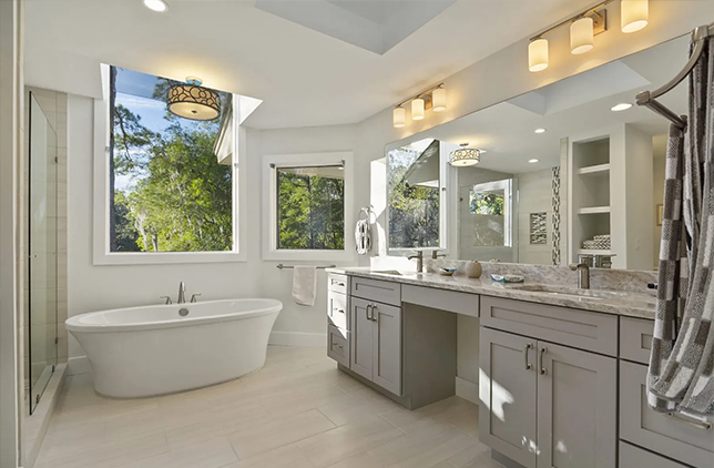 Bathroom with arched window, freestanding tub, shower, and dark wood floor.
