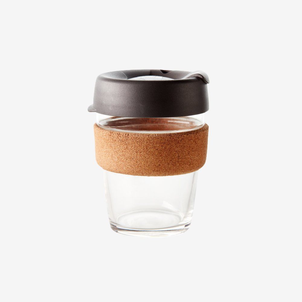 Glass reusable coffee cup with a black lid and cork sleeve.