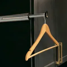 Wooden hanger hanging from a clothes rod inside a dark closet.