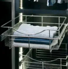 Chrome wire basket with folded clothes inside a closet.