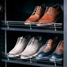 Shoe rack in a dark closet holding several pairs of men’s dress shoes in brown and gray.