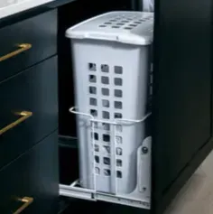 Laundry hamper on a pull-out track inside a black cabinet with gold handles.