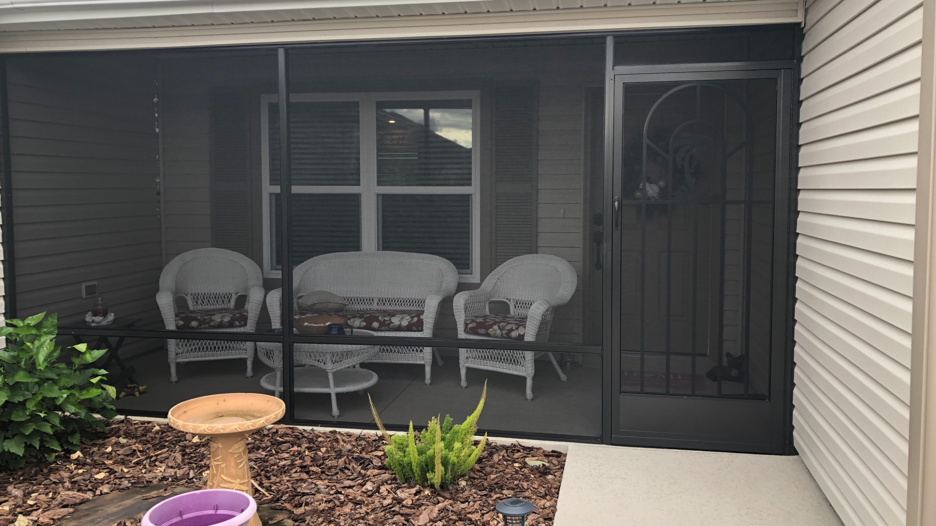 A white pergola is sitting in front of a house.