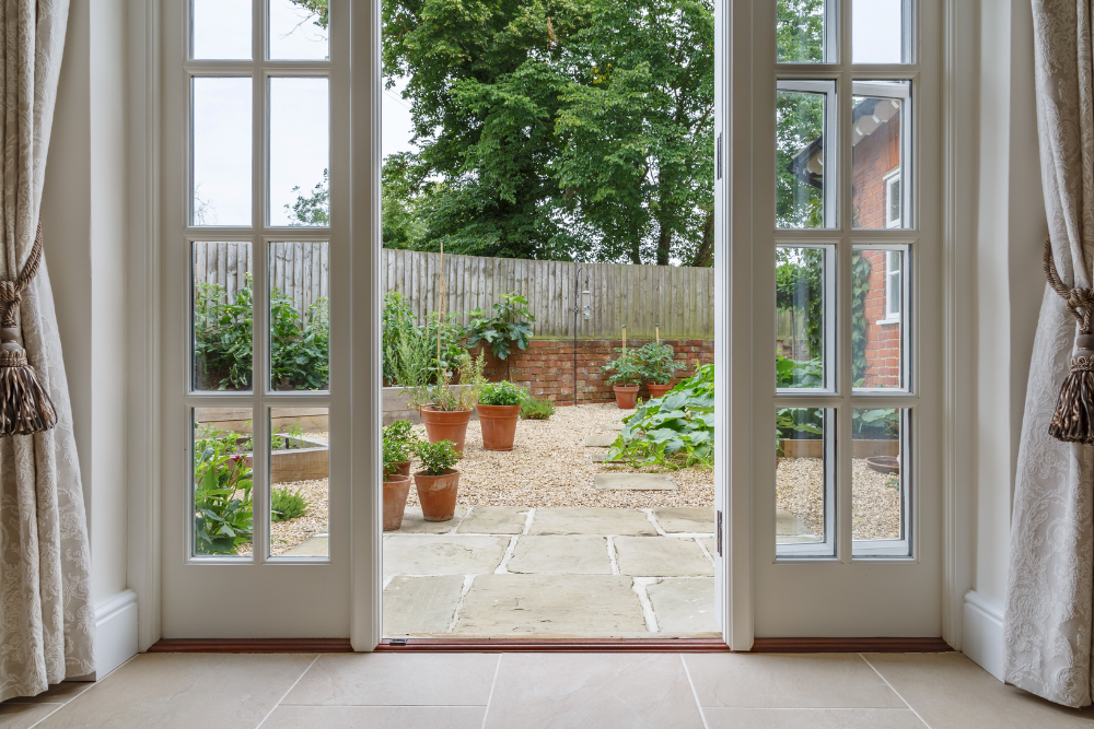A room with a view of a garden through the sliding glass doors.