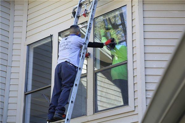 A man is standing on a ladder cleaning a window.