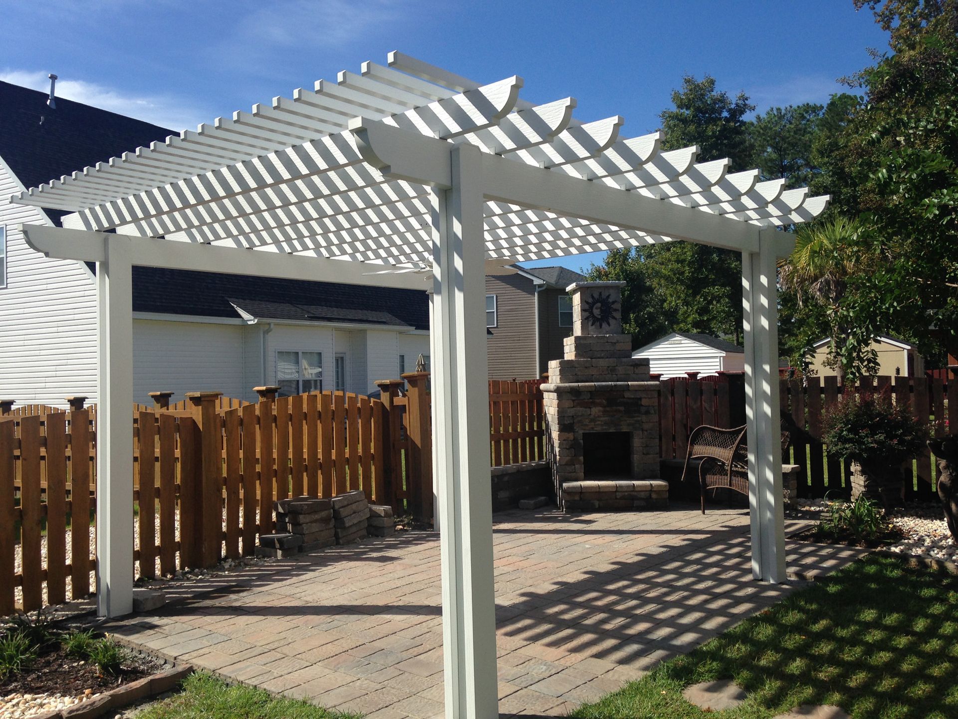 A white pergola is in the backyard of a house