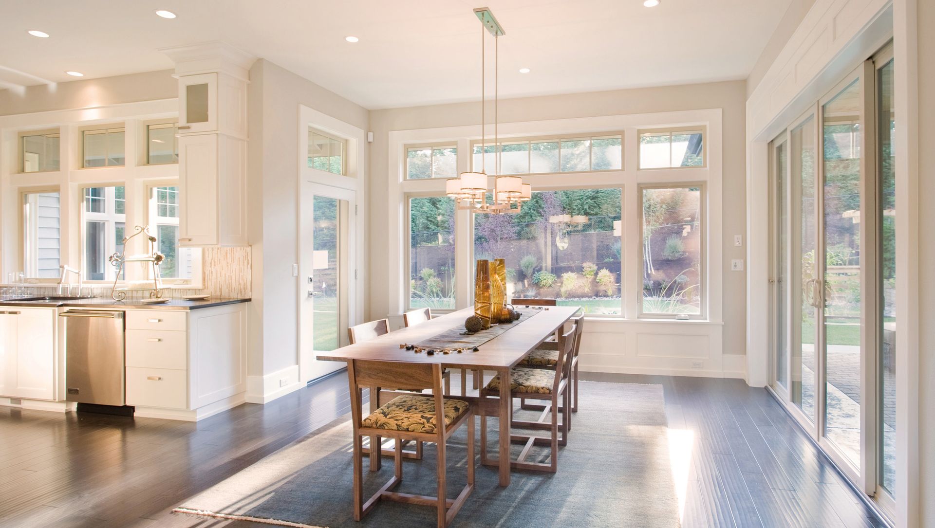 A dining room with a long table and chairs and lots of windows