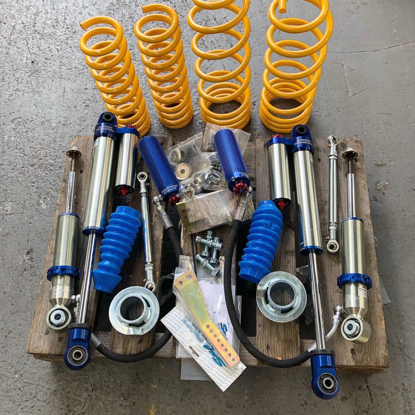Yellow and Blue Suspension Lift Kit on a Wooden Pallet — Atlas 4X4 Touring & Mechanical in Tweed Heads, NSW