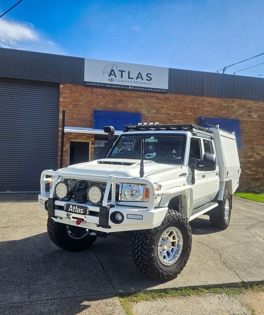 White off-road vehicle with large tyres parked outside an Atlas sign on a brick building  — Atlas 4X4 Touring & Mechanical in Tweed Heads, NSW